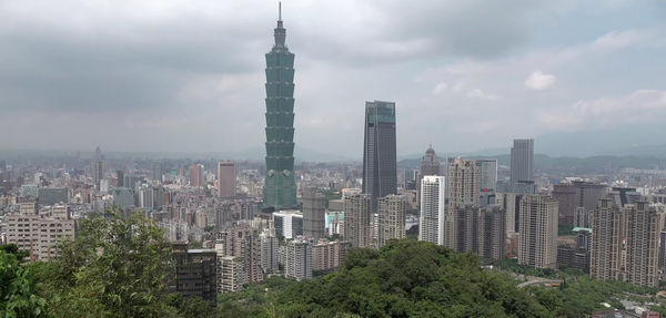 Modern buildings in city against cloudy sky