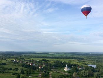 Hot air balloon flying over field against sky