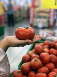 Cropped image of hand holding tomatoes at market stall