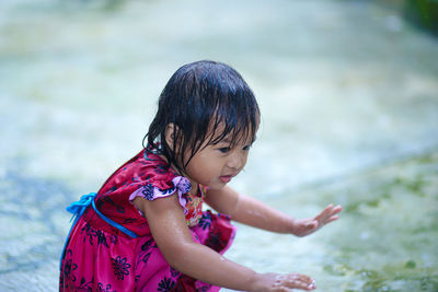 Side view of girl crouching by water