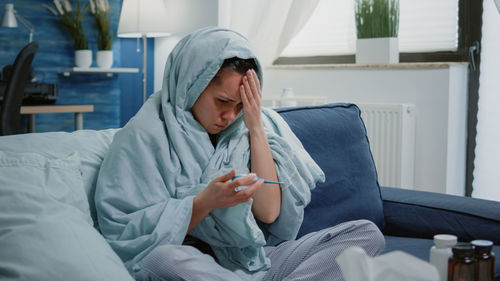 Young woman sitting on bed at home