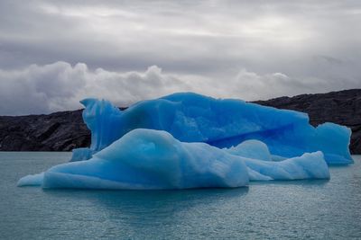Scenic view of icebergs against cloudy sky
