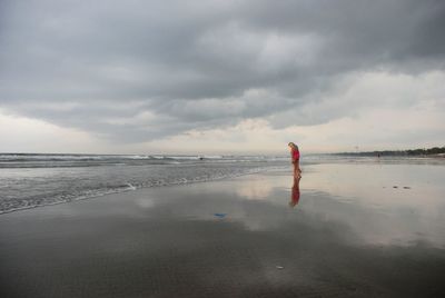 Man standing on beach against storm clouds