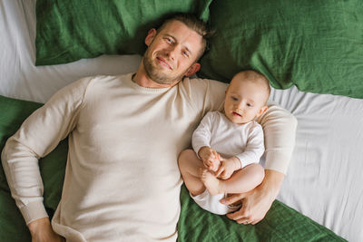Happy father is lying on the bed with his little child. conception of family, fatherhood and people