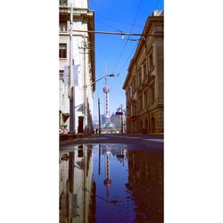 Reflection of buildings in puddle against sky