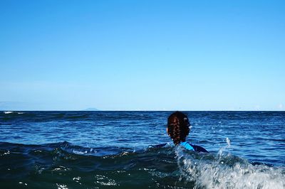 Rear view of woman in sea against clear sky