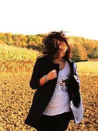 Woman holding umbrella while standing on field against sky