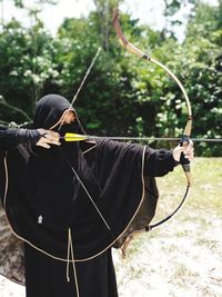 Woman aiming with archery on field