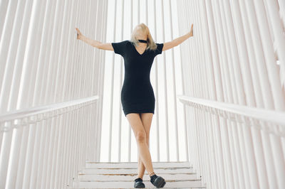 Full length of woman standing on steps amidst railing