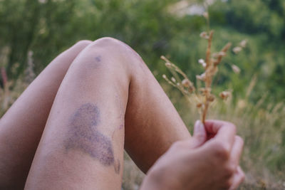 Low section of woman lying on grassy field