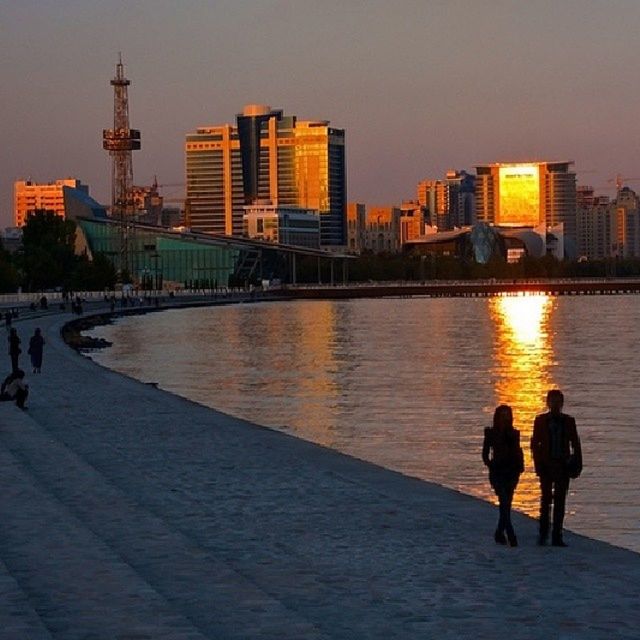 building exterior, architecture, built structure, city, water, sunset, lifestyles, leisure activity, men, full length, city life, person, walking, sky, river, silhouette, orange color, reflection