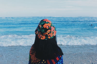 Rear view of woman standing by sea against sky