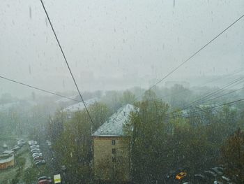 View of buildings seen through wet window during rainy season