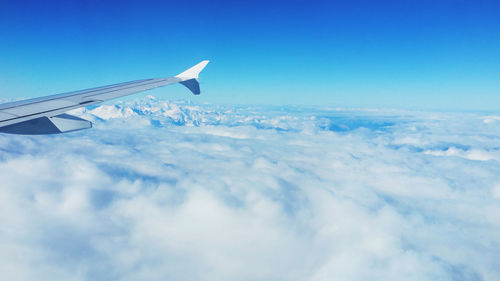 Airplane flying over cloudscape against blue sky