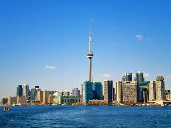 City at waterfront against blue sky