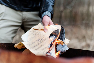 Midsection of man burning paper outdoors