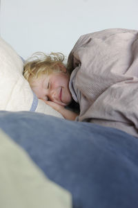 Smiling girl with eyes closed relaxing in bed