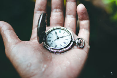 Close-up of human hand holding clock