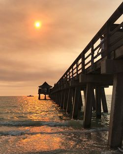 Pier over sea against sky during sunset