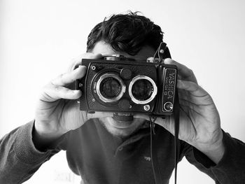 Portrait of man photographing with camera against white background