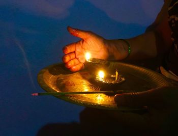 Midsection of woman protecting illuminated oil lamp