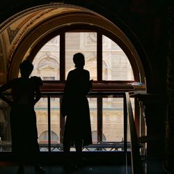 Rear view of silhouette man looking through window