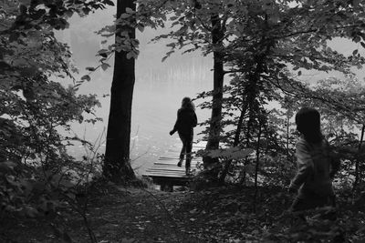 Rear view of siblings playing at lakeshore