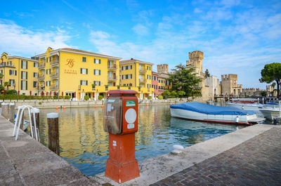 Buildings by river against blue sky