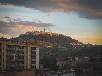 Houses in town against sky during sunset