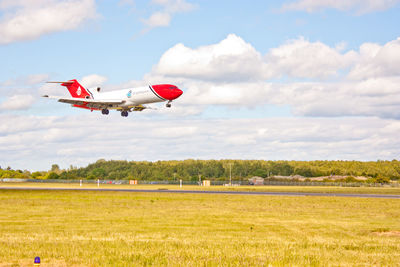 Airplane flying over field against sky