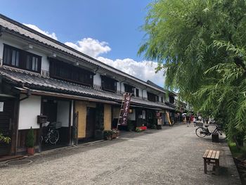 Street amidst trees and buildings against sky