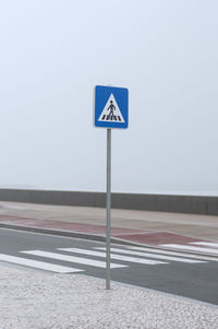 Road sign on street against clear sky