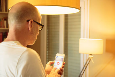 Rear view of man using mobile phone at home