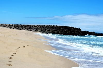 Scenic view of beach against cloudy sky