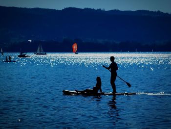 Silhouette people on sea against sky