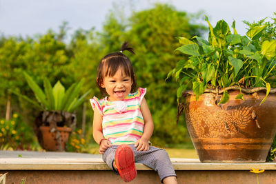 Cheerful baby girl laughing while sitting in yard