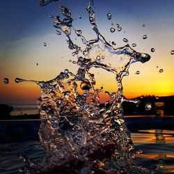 Close-up of water drops on silhouette tree against sea