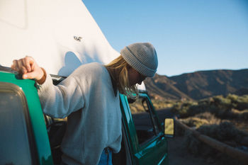 MIDSECTION OF WOMAN SITTING AGAINST BLUE SKY AND MOUNTAINS