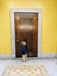 Side view of boy standing by closed door at home