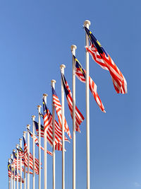 Low angle view of flags against clear blue sky