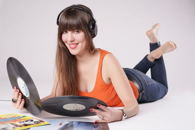 Portrait of smiling beautiful woman holding records against white background