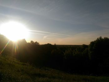 Scenic view of field against bright sun during sunset