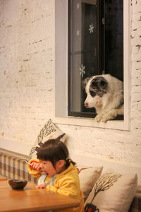 Asian girl eating chinese food while dog watches at the window