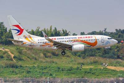 Airplane flying over runway against sky