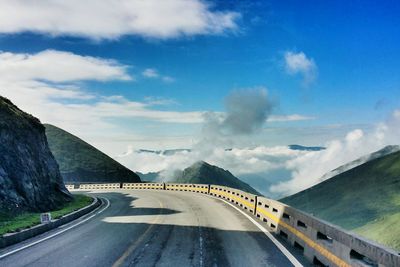 Road leading towards mountains against sky