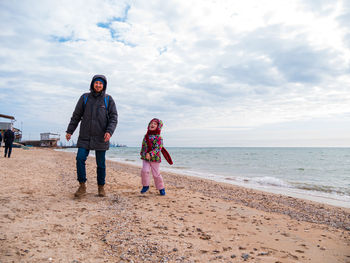 Father daughter walking running on beach. lifestyle real people blue sea sky happy family having fun 