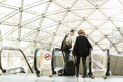 Business people moving down escalator in railroad station