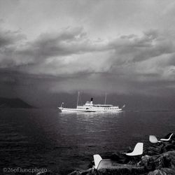 Boats sailing in sea against cloudy sky