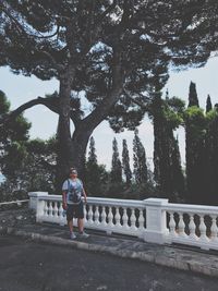 Portrait of man standing by railing against trees