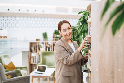 Adult smiling brunette business woman forty years in stylish beige suit and jeans at public place